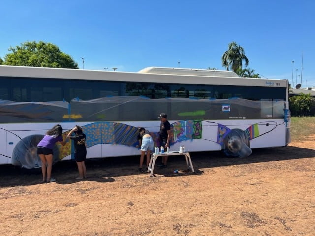 Youths Working Together To Paint A Mural On The Side Of The Buslink Bus